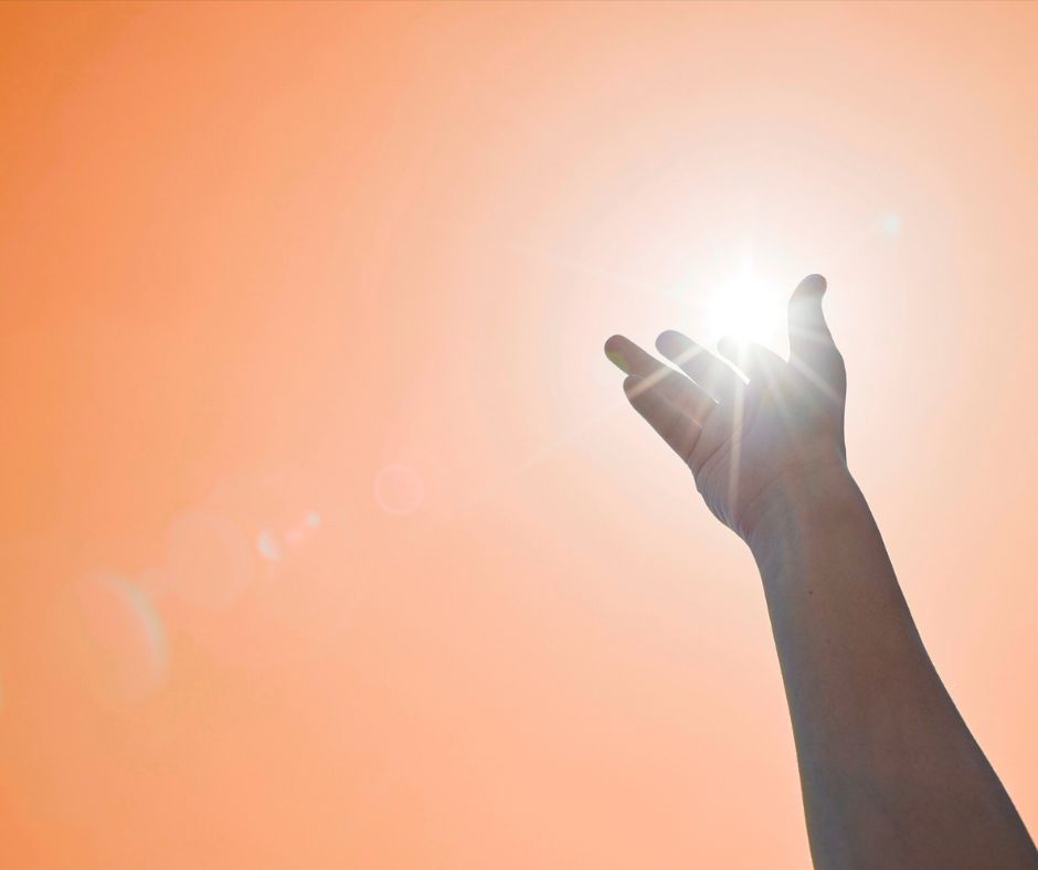 main vers le ciel orangé avec soleil en arrière plan